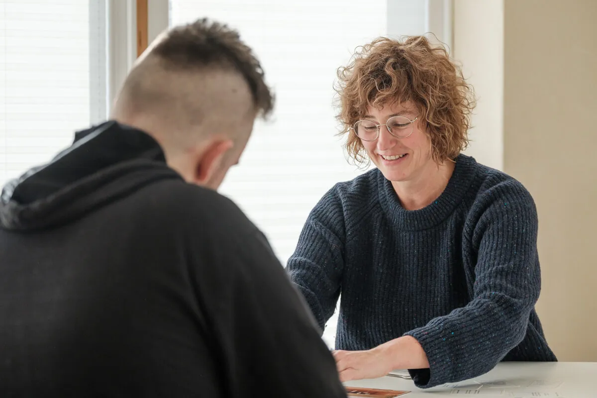 Carola Körner sitzt mit einem jugendlichen Patienten an einem weißen Tisch und spielt ein Rollenspiel mit Karten