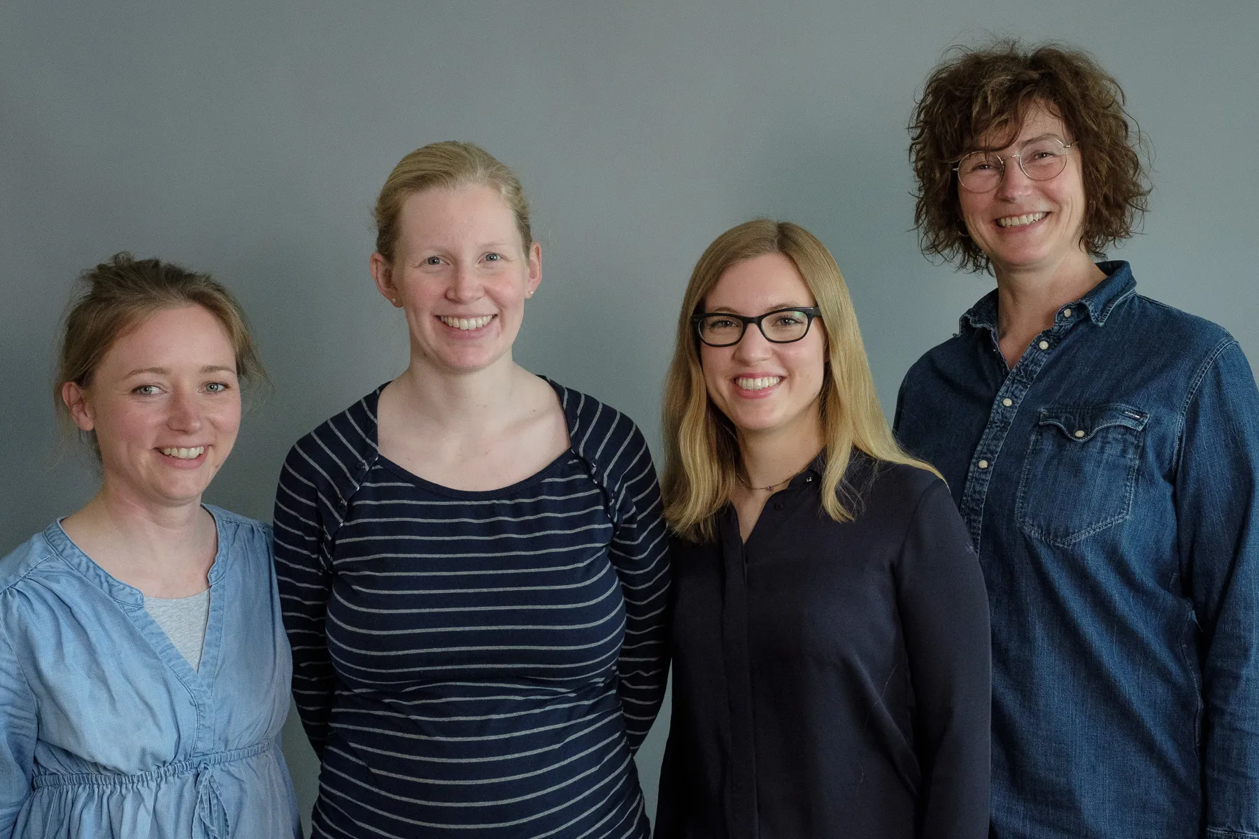 Carola Körner steht mit ihrem Team vor einem grauen Hintergrund